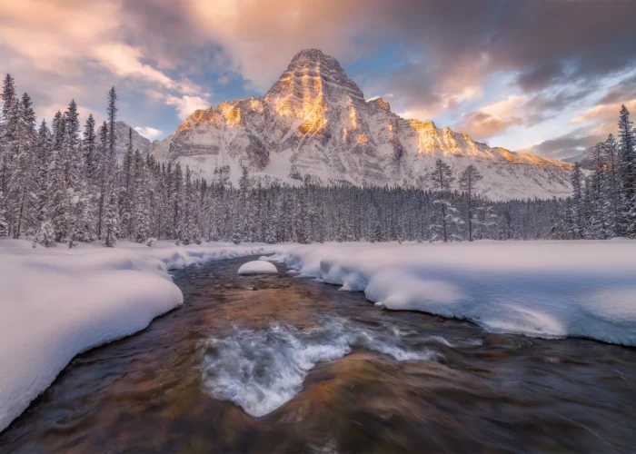 A landscape photograph of Mount Chephren in the Canadian Rockies during a winter sunrise