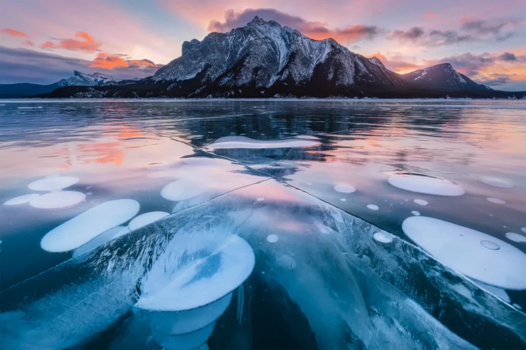 A landscape photograph of methane bubbles on abraham lake during sunrise in the winter